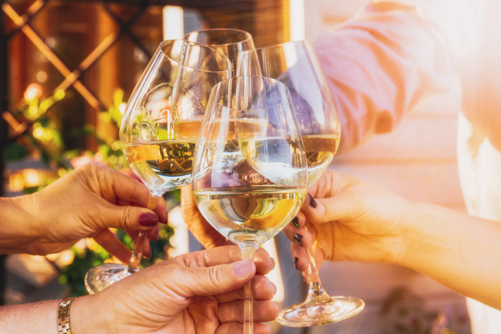 Group clinking wine glasses with dry white wine